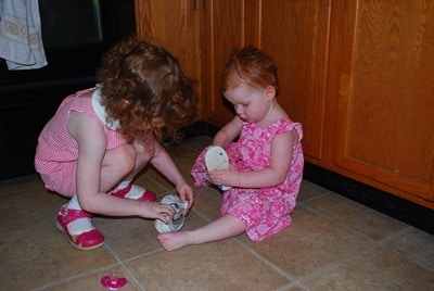 Izzy helps put Nat's shoes on.
